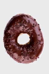 Chocolate crunch doughnut, top view. Yummy dessert with chocolate icing on white background.