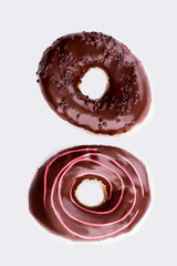 Two chocolate donuts on white background. Pair of donuts, top view. High calorie dessert.