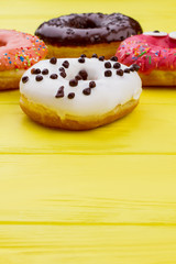 Donuts on color wooden background with copy space. Glazed round cakes. Delicious sweets with frosting.