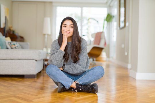 Young beautiful woman sitting on the floor at home thinking looking tired and bored with depression problems with crossed arms.