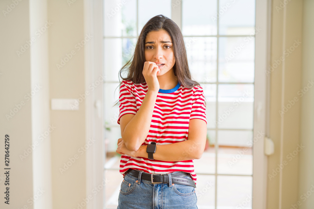 Poster Young beautiful woman wearing casual t-shirt looking stressed and nervous with hands on mouth biting nails. Anxiety problem.