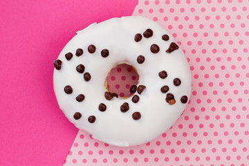 White donut on pink patterned background. Cake with chocolate sprinkles. Delicious homemade snack.