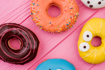 Colorful donuts on pink wooden background. Fresh donuts with delicious glaze.