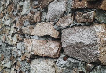 Fragment of a wall from a natural stone. Granite and cement.