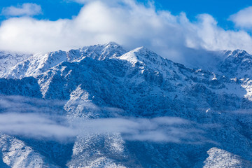 Fototapeta na wymiar Cerro Ramon and Cerro La Cruz summits during a winter day. Snowcapped summits at central Andes mountains and amazing snowy rugged landscape on a cloudy day, an awe outdoor winter background scenery 