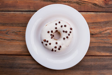 White glazed donut on plate, top view. Frosted cake for breakfast. Unhealthy food concept.