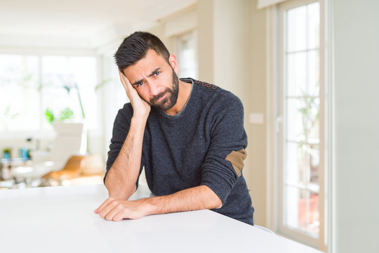 Handsome hispanic man wearing casual sweater at home thinking looking tired and bored with depression problems with crossed arms.