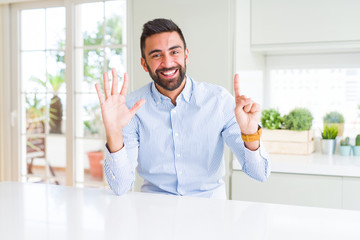 Handsome hispanic business man showing and pointing up with fingers number six while smiling confident and happy.