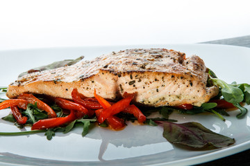 closeup roasted sea fish with green salad and arugula