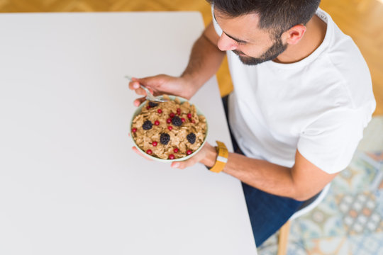 Above angle of handsome man eating healthy cereals for breakfast in the morning