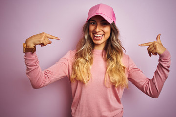 Young beautiful woman wearing cap over pink isolated background looking confident with smile on...