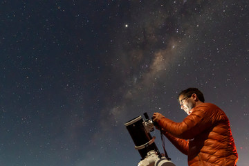 One astronomer man looking the night sky through an amateur telescope and taking photos with the...