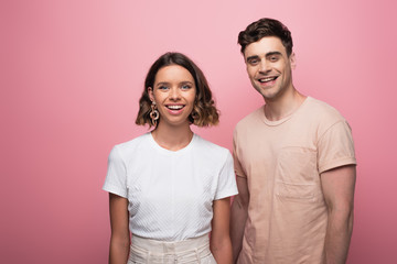 Naklejka premium young, cheerful man and woman looking at camera on pink background