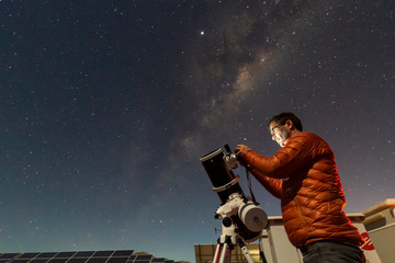 One astronomer man looking the night sky through an amateur telescope and taking photos with the Milky Way rising over the horizon, an amazing night view at Atacama Desert - obrazy, fototapety, plakaty