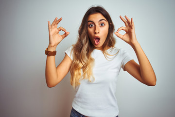 Young beautiful woman wearing casual white t-shirt over isolated background looking surprised and...