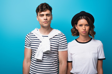Obraz premium young, disappointed man and woman looking at camera on blue background