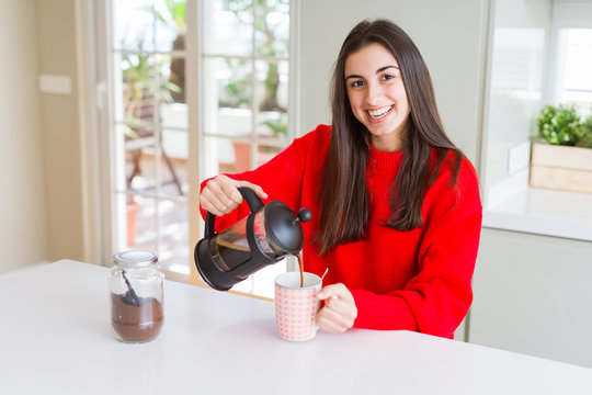 Young beautiful woman making morning coffee smiling, preparing a cup of latte for breakfast