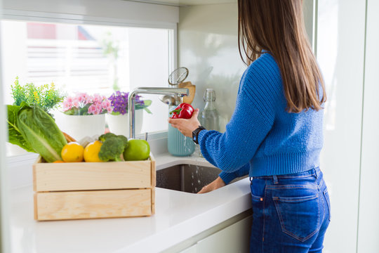 Young woman washing vegetables and fruit using water from sink