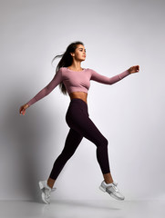 Obraz premium Young athletic woman brunette girl in a good shape in trendy sportswear walking in gym uniform does cardio exercises 