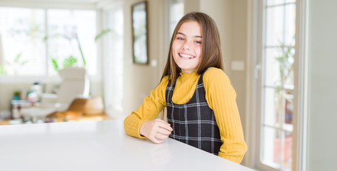 Beautiful young girl kid sitting on the table with a happy and cool smile on face. Lucky person.