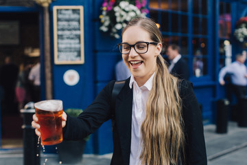 Young business lady in glasses standing by the pub with a pint of the beer.