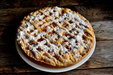 Homemade apricot pie in a white plate on a wooden table.