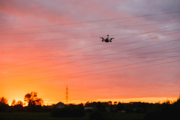 Custom made drone flying on sunset near power lines. Concept modeling, detection of obstacles