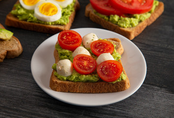 Tomato and Mozzarella Avocado Toast on a Wooden Table