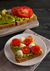 Tomato and Mozzarella Avocado Toast on a Wooden Table