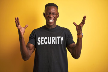 African american safeguard man wearing security uniform over isolated yellow background celebrating...