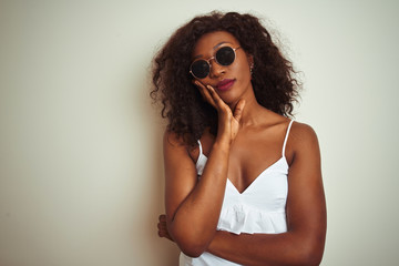 Young african american woman wearing t-shirt and sunglasses over isolated white background thinking looking tired and bored with depression problems with crossed arms.