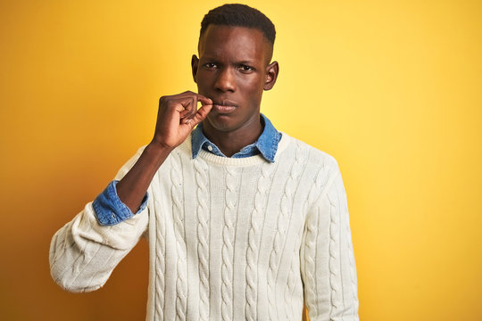 African american man wearing denim shirt and white sweater over isolated yellow background mouth and lips shut as zip with fingers. Secret and silent, taboo talking