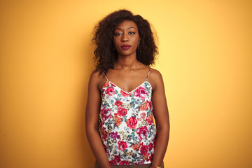 African american woman wearing floral summer t-shirt over isolated yellow background Relaxed with serious expression on face. Simple and natural looking at the camera.