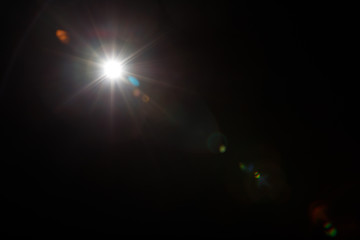 Lens Flare. Light over black background. Easy to add overlay or screen filter over photos. Abstract sun burst with digital lens flare background. Gleams rounded and hexagonal shapes, rainbow halo.