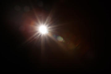 Lens Flare. Light over black background. Easy to add overlay or screen filter over photos. Abstract sun burst with digital lens flare background. Gleams rounded and hexagonal shapes, rainbow halo.