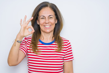 Obraz na płótnie Canvas Middle age senior woman standing over white isolated background smiling positive doing ok sign with hand and fingers. Successful expression.