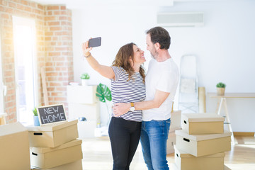 Middle age senior romantic couple taking a selfie picture with smartphone smiling happy for moving to a new house, making apartment memories