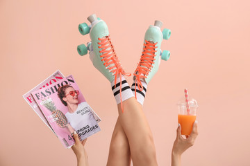 Woman in vintage roller skates, with fashion magazines and juice on color background