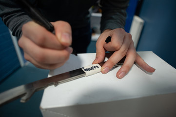 Ice hockey equipment: ice hockey equipment manager writing notes on ice skate blades