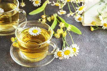 Cup of hot chamomile tea on grey table