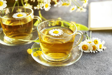 Cups of hot chamomile tea on grey table