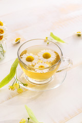 Obraz na płótnie Canvas Cup of hot chamomile tea on wooden table