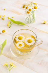 Obraz na płótnie Canvas Cup of hot chamomile tea on wooden table