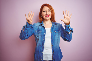Youg beautiful redhead woman wearing denim shirt standing over isolated pink background showing and...
