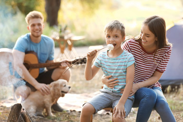 Obraz premium Mother and her little son roasting marshmallow on fire in forest