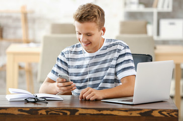 Male student listening to music while preparing for exam