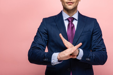 cropped view of businessman in formal wear showing reject gesture on pink background