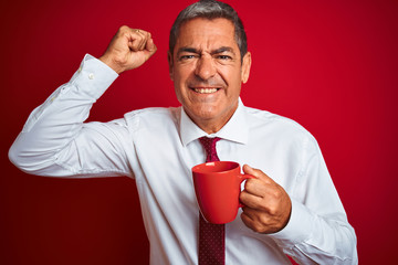 Handsome middle age businessman holding cup of coffee over isolated red background annoyed and frustrated shouting with anger, crazy and yelling with raised hand, anger concept