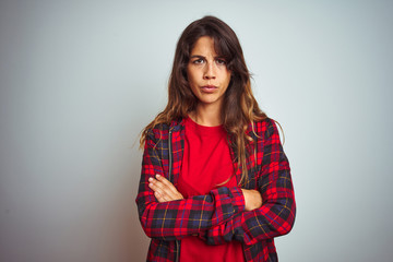 Young beautiful woman wearing red t-shirt and jacket standing over white isolated background skeptic and nervous, disapproving expression on face with crossed arms. Negative person.