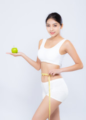 Beautiful asian woman diet and slim with measuring waist for weight and holding green apple fruit isolated on white background, girl have calories loss with tape measure, health and wellness concept.